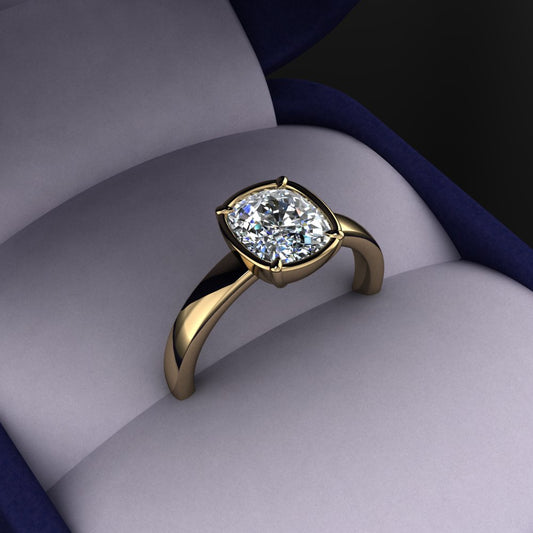 Gold ring with a cushion shaped diamond in a navy blue and grey fabric ring box
