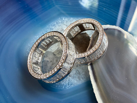 Two platinum and lab diamond men's rings laying on a piece of blue agate