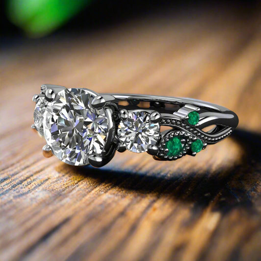 1.5 carat round three stone ring with green moissanite accent stones on a wooded table