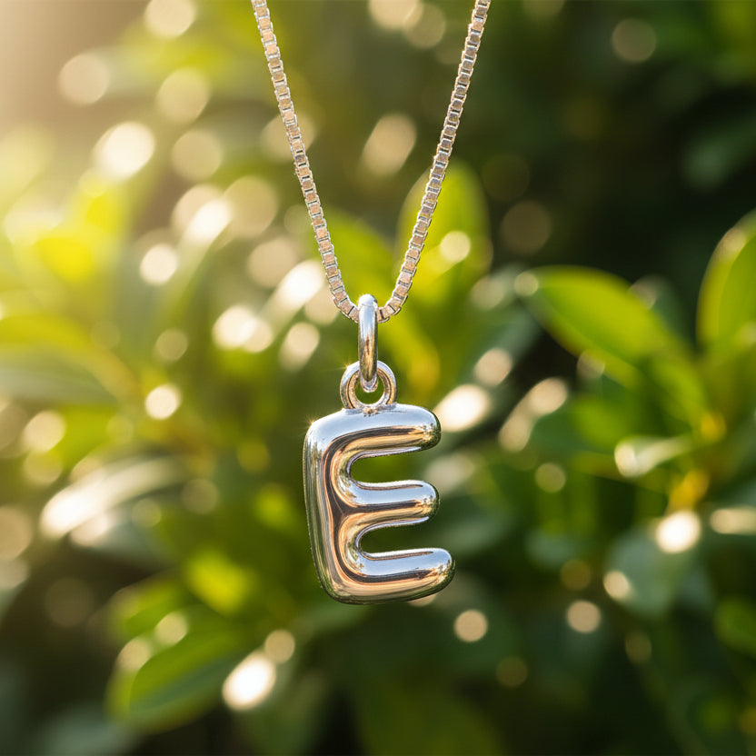 Silver necklace with a bubble letter 'E' pendant on a white background