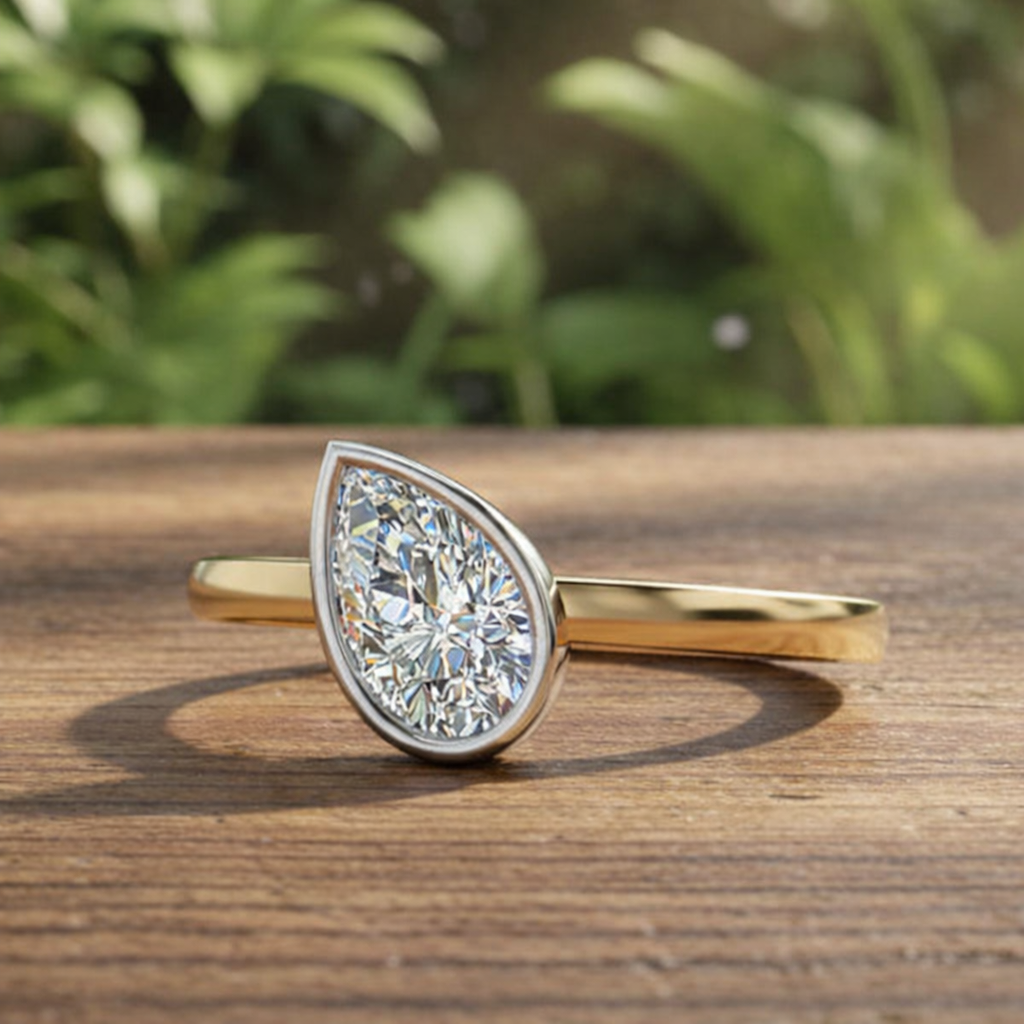 Gold ring with a pear-shaped diamond on a wooden surface with a blurred green background