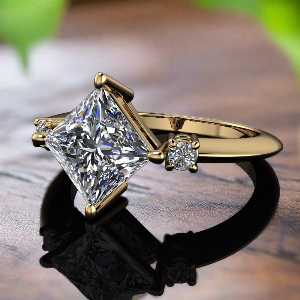 1.5 carat princess cut engagement ring, with 3 stones. Laying on a wood table with leaves in the background.