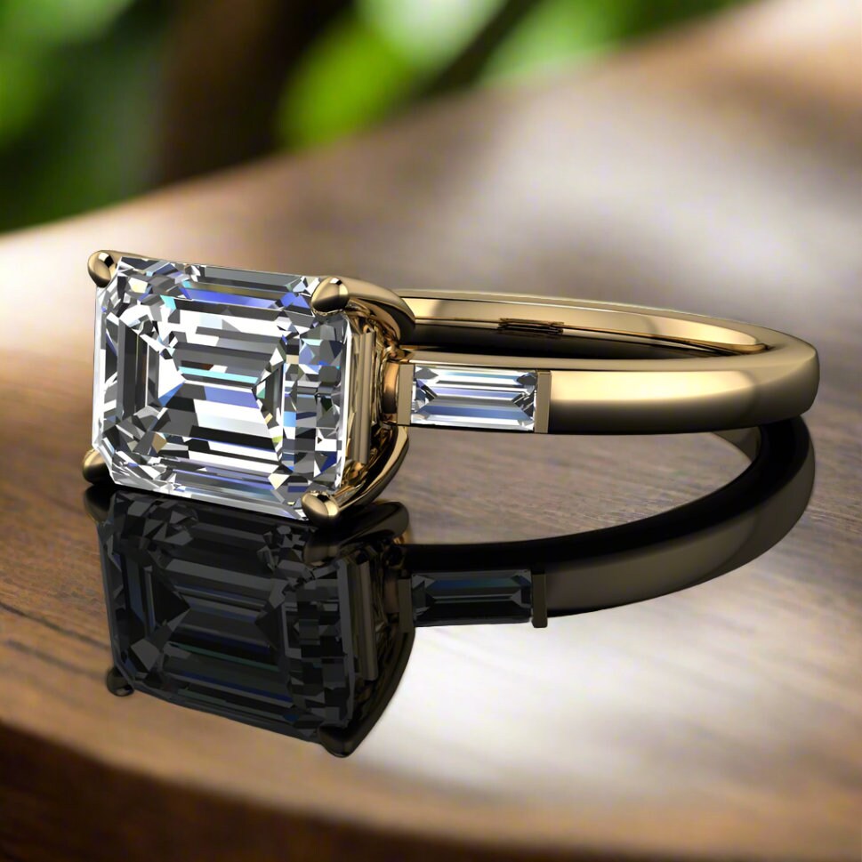 1.5 carat lab grown diamond emerald cut engagement ring, east west engagement ring, three stone ring - laying on a table