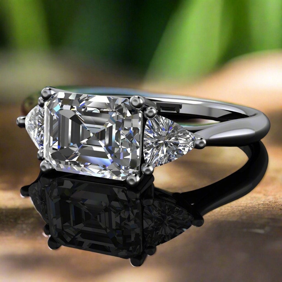 Emerald cut 3 stone moissanite engagement ring - flat on table
